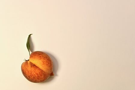 Ripe yellow-red peach with green leaf. With half longitudinal division in half. On a light background below left.の写真素材