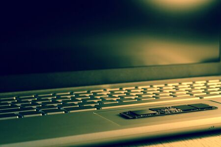 Chip SSD-drive on the trackpad. Partially in sharpness. The keyboard is partially blurred, side view from the bottom. A photo using a blue color filter is a process. All lines are parallel diagonally.の写真素材