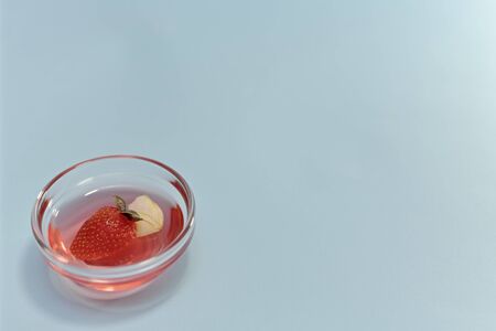 Strawberry glitter jelly with apple and basil in transparent rosette dish. bottom left on a blue background tilted.の写真素材
