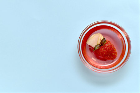 Jelly with strawberries, apples and basil in a transparent rosette. Right on a blue background, a...