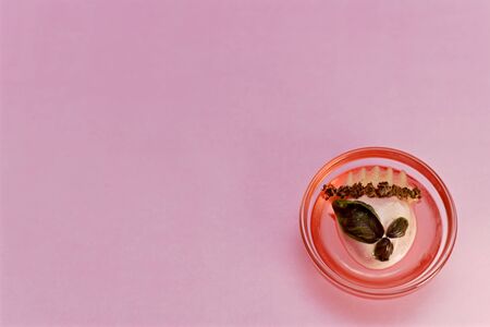 Originally decorated dessert of pink ice cream, red jelly, corrugated apple with chocolate chips and basil leaves. In the outlet on a pink background in the lower right corner.の写真素材