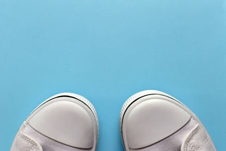 Edges of white rubber textile footwear partially peeking out from underneath. With a thin black line along the contour of the sole. Socks together. On a light blue empty background.の写真素材
