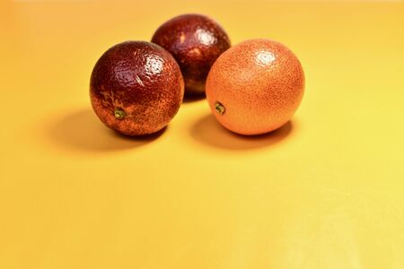 3 red oranges in the center from above on a yellow substrate. Located close to each other. Glossy shiny skin.の写真素材
