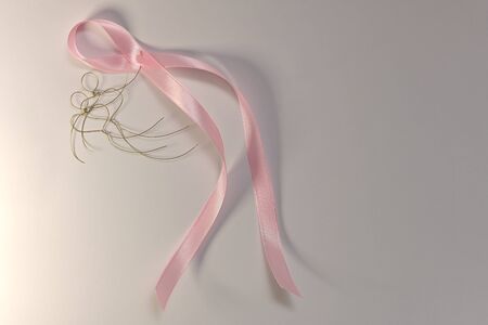 A pink ribbon in the hands of a flying pair of wire hearted little men.の写真素材