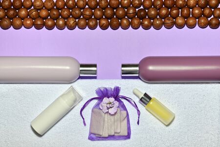 A horizontal row of macadamia nuts lined at the top and a row of perfume bottles and a terry towel below.の写真素材