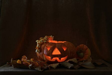 Instructions on how to make a pumpkin lamp for the Halloween holiday. Cleanse the seeds, cut out the eyes, nose and mouth, light candles.の素材 [FY310129775510]