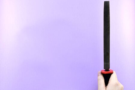 File in the hand, the back of the brush, located vertically, on the right, on a purple background.の写真素材