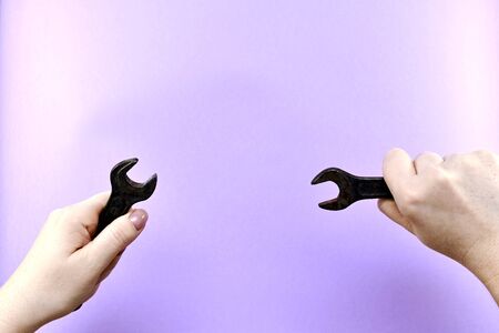 Two women hands, with horn wrench in each, right and left, on a light purple background, with free space.の写真素材