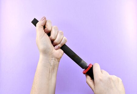 Two women hands tightly squeeze the file, against a purple background.の写真素材