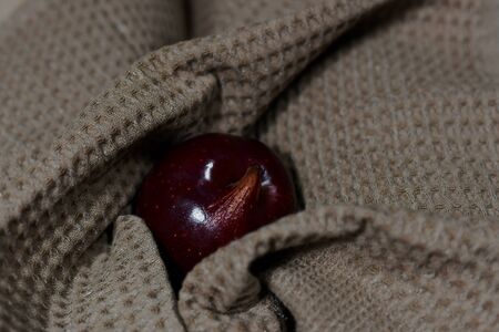 The dark red apple is irregularly shaped in a smoky waffle towel.の写真素材