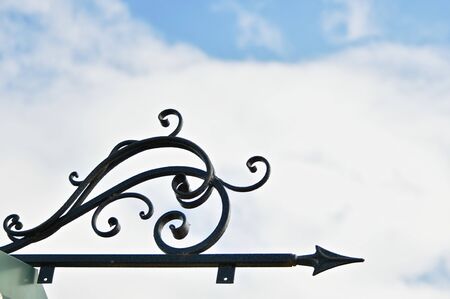 The black forged arrow from below the frame is directed to the right, against the cloud blue sky.の写真素材