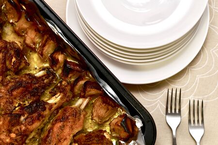 Spirit wings of turkey in apples and fat on the table in a roasting pan on a cotton beige tablecloth with small plates and forks, a view from above.の写真素材
