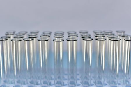 Test tubes are even horizontal rows, illuminated by light and shining on a light purple background, top view from the front.の写真素材