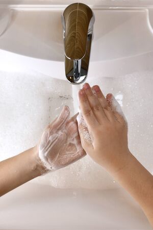 A child clumsily masters the technique of soaping hands with soap suds.の写真素材