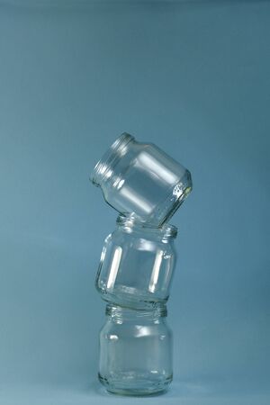 Three glass jars lined with curved pyramid towers on a vertical blue background.の写真素材