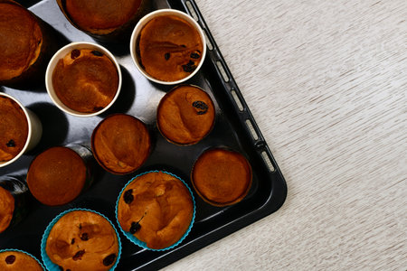 Easter cakes, crispy brown, with raisins, in small various round shapes. On the black oven tray, on...