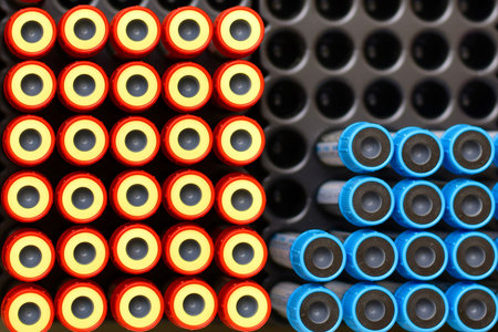 View from above on the lids of disposable test tubes used for venous blood tests. On a black plastic...