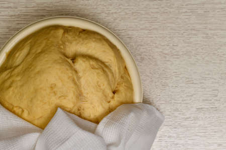 Ferment the dough in a bowl on the table under a cotton white towel, slightly ajar. Left below. View from above.の写真素材