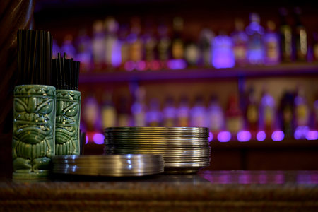 View from the bar, on the shelves with bottles in a blur form with lights side of purple color, on...