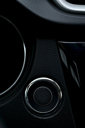 Fragment of a part of a black car panel with leather trim. Round button start and stop ignition.の写真素材