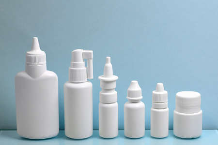 A diverse set of white plastic containers for pharmacy drugs, lined up in order of size in height. On a light blue background.の写真素材