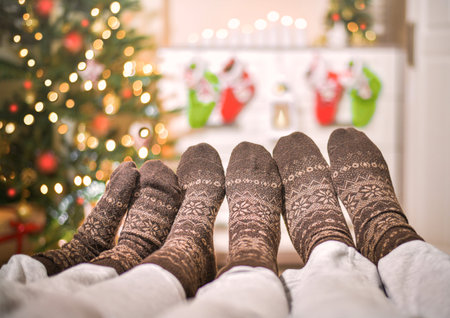 Three pairs of different leg ages in woolen socks. At Christmas, opposite a decorated sparkling...