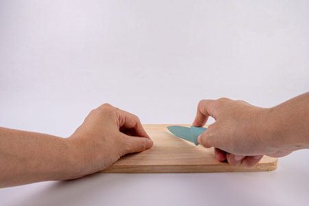 Close-up - hands with a knife on a wooden board,white background