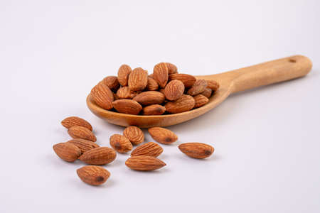 Almonds on wooden spoon isolated over white backgroundの写真素材