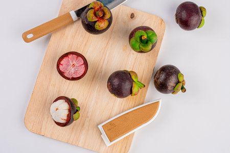 Mangosteen fruit and knives on a wooden chopping board on wood table.の写真素材