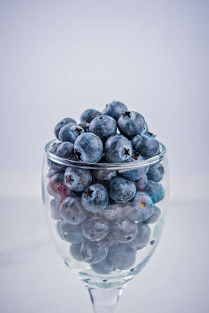 Blueberries in a glass of wine on white background.の写真素材