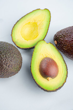 Fresh organic avocado cut in half separated on white table