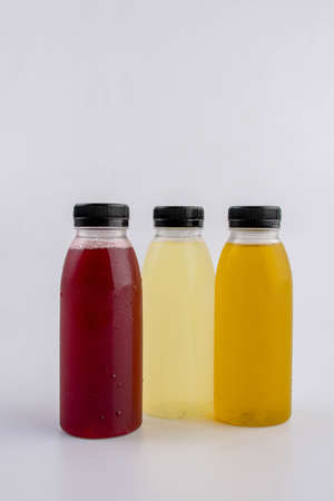 Three bottles of orange, red and yellow juice on a white backgroundの写真素材