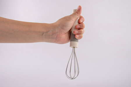 hand holding whisk egg isolated on white backgroundの写真素材