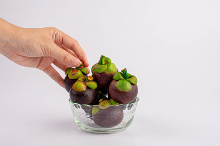 Person holding a bowl of fruit,Mangosteen with glass cup on white background.