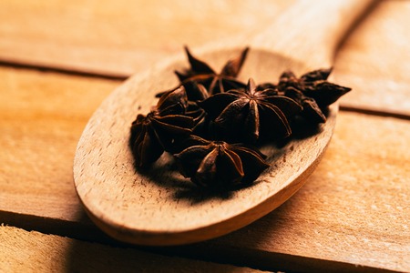 star anise spice in a wooden spoon on a light background.の写真素材