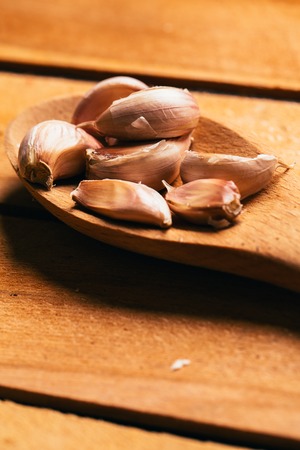 Garlic in a wooden spoon on a light background.の写真素材