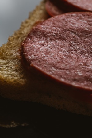 sandwich with smoked sausage on a dark background.の写真素材