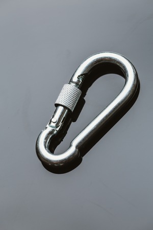 one metal carabiner on a dark mirroring background.の写真素材
