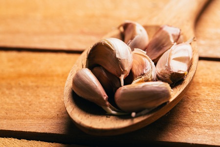 Garlic in a wooden spoon on a light background.の写真素材