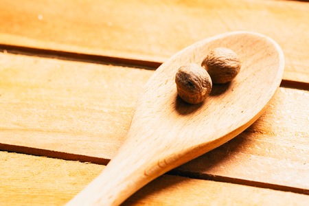 Nutmeg in a spoon on a wooden background.の写真素材