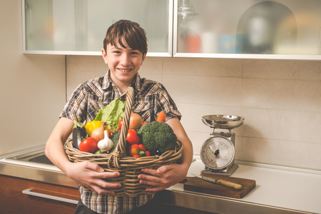 boy prepares vegetables in the kitchen - vegetarian healthy peopleの写真素材