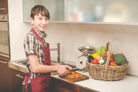 boy prepares vegetables in the kitchen - vegetarian healthy peopleの写真素材