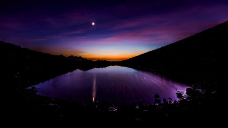 beautiful mountain landscape at sunset with moon and little lake
