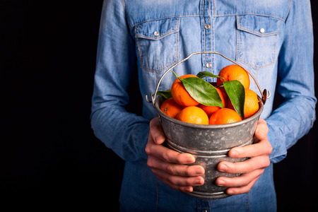 tangerines bucket in hands - vegetarian and vegan peopleの写真素材