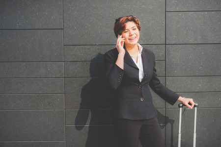 young authentic business woman talks on her smartphone in the financial district for business tripの写真素材
