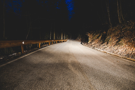 the headlights of a car on mountain road in the night - concept driving safetyの写真素材