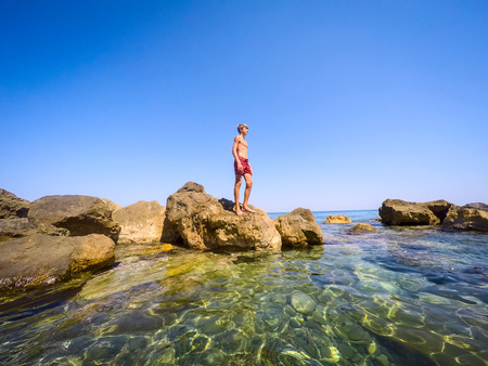 teenager standing on the rocks at seaside - summertime - Sicily mediterranean seaの写真素材