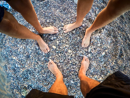 feet of teenagers sons and father on the beach to the sea - summertime - Sicily mediterranean seaの写真素材