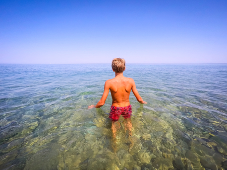 teenager ready to swim in the sea - summertime - Sicily mediterranean seaの写真素材