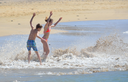 Children playing in waves on Papagayo beach.のeditorial素材